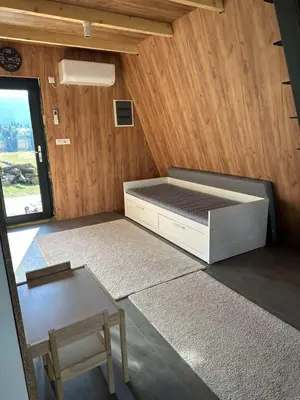 a small bedroom with a bed and a table at A Frame house Slavuljica in Vlasic