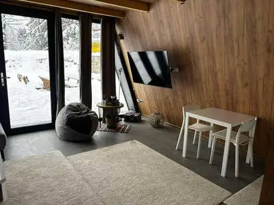 a living room with a table and chairs and a window at A Frame house Slavuljica in Vlasic