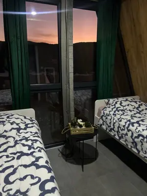 a bedroom with two beds and a table and a window at A Frame house Slavuljica in Vlasic