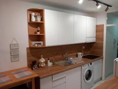 a kitchen with white cabinets and a washing machine at Apartman AM Tuzla in Tuzla