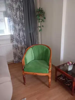 a green chair in a living room with a table at SlatinaApartman in Tuzla