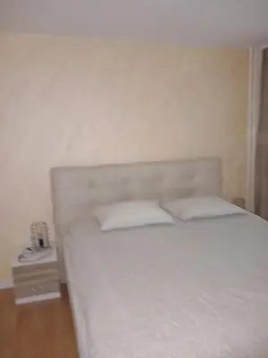 a bedroom with a white bed and a night stand at SlatinaApartman in Tuzla