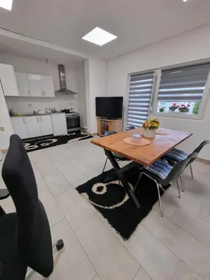 a living room with a wooden table and chairs at Sobe Kod Ćobe in Matuzići