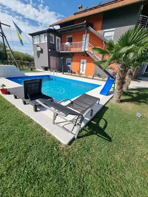 a swimming pool in front of a house at Sobe Kod Ćobe in Matuzići