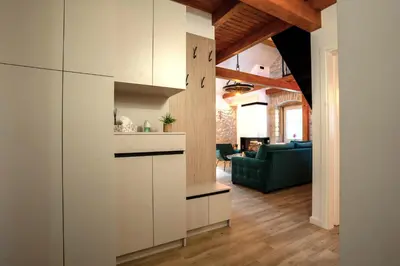 a kitchen with white cabinets and a living room at Apartman Rustic Charm in Livno