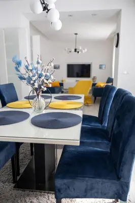 a dining room with blue chairs and a white table at Una Riverside Heritage House in Bihać
