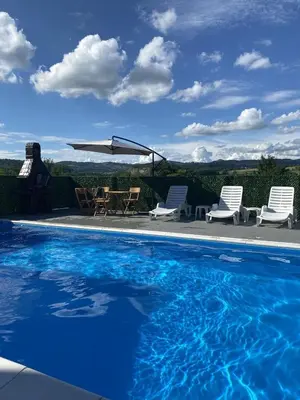 a swimming pool with chairs and a table and a umbrella at Vikend kuća Ljetni San in Gračanica