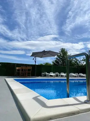 a pool with an umbrella and chairs and a table at Vikend kuća Ljetni San in Gračanica