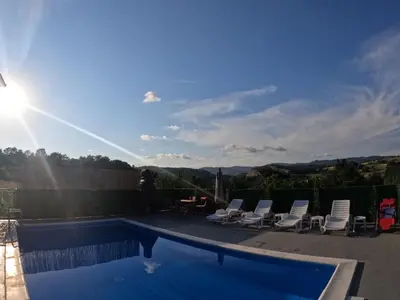 a swimming pool with chairs and the sun in the sky at Vikend kuća Ljetni San in Gračanica