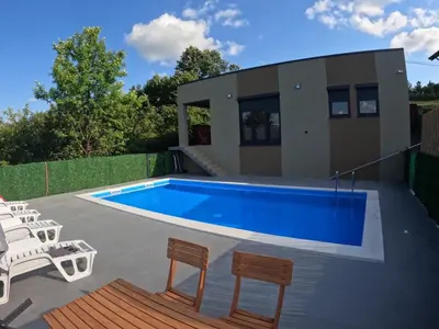 a swimming pool with chairs and a house at Vikend kuća Ljetni San in Gračanica