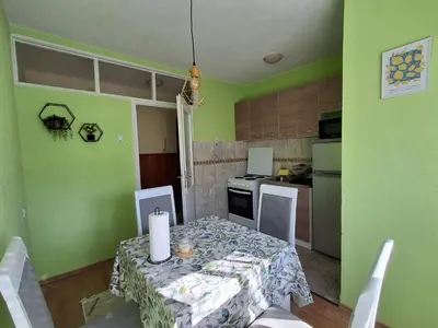 a kitchen with a table and chairs and a kitchen with green walls at Na korak do Vrbasa - blizu centra in Banja Luka