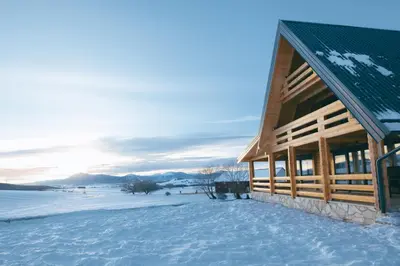 a log cabin in the snow with the sun setting at Villa Alba in Kupres