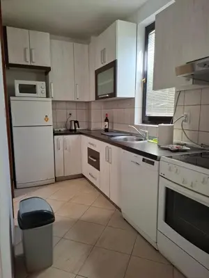 a kitchen with white appliances and a trash can at Apartman Atlas in Doboj