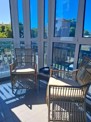 three chairs and a table in a room with windows at Apartman Atlas in Doboj