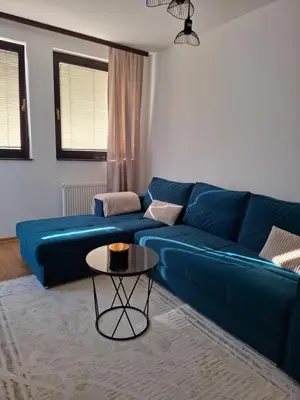 a blue couch in a living room with a table at Apartman Atlas in Doboj