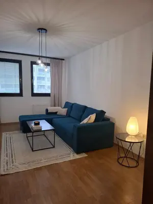 a living room with a blue couch and two tables at Apartman Atlas in Doboj