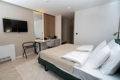 a bedroom with a bed with white pillows and a desk at Hotel Cat Deluxe in Sanski most