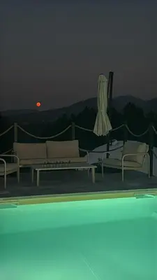 a view of a pool with two couches and a umbrella at Balun BLKN in Ostrožac