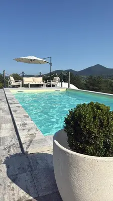 a blue swimming pool with a planter and an umbrella at Balun BLKN in Ostrožac