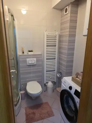 a bathroom with a toilet and a washing machine at Apartman Dora'K in Doboj