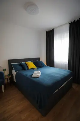 a bedroom with a bed with blue sheets and a window at Apartman za 5 in Banja Luka
