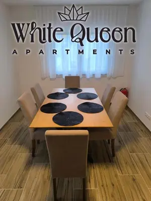 a table with chairs and a sign that reads white orphanant at White Quenn Apartments in Sanski most