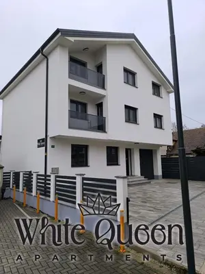 a white apartment building with a sign in front of it at White Quenn Apartments in Sanski most