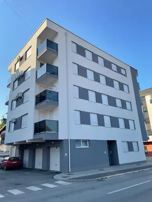 an apartment building on a street with a parking lot at Apartment Welcome in Modriča