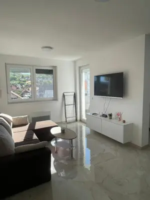a living room with a couch and a tv on a wall at Apartment Welcome in Modriča