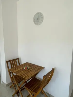a table and two chairs and a clock on a wall at Apartment Welcome in Modriča