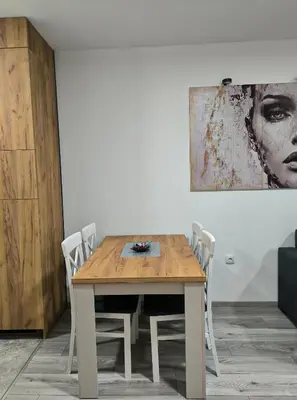 a wooden table with chairs in a room with a painting at Apartman Prijedor in Prijedor