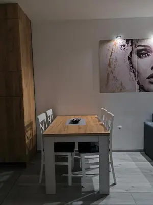 a dining room table with white chairs and a painting at Apartman Prijedor in Prijedor