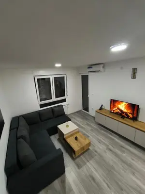 a living room with a black couch and a fireplace at Apartman Prijedor in Prijedor