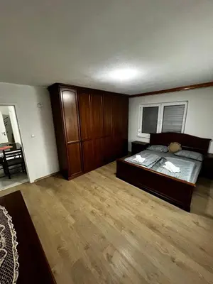 a bedroom with a large bed and wooden cabinets at Sweet Home in Tuzla