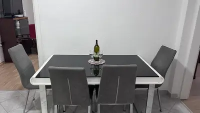 a dining room table with a bottle of wine and chairs at Sweet Home in Tuzla