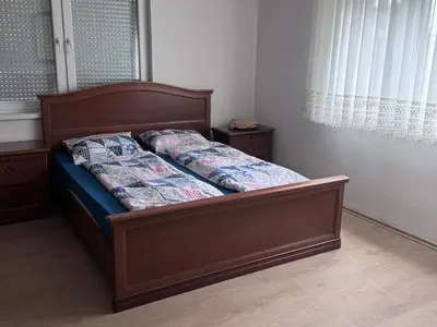 a bed with a wooden frame in a bedroom at Sweet Home in Tuzla