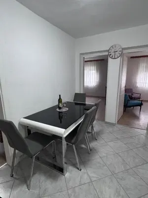 a dining room with a table and chairs and a clock at Sweet Home in Tuzla