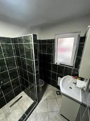 a bathroom with a black tiled shower and a sink at Sweet Home in Tuzla