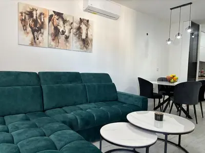 a living room with a green couch and tables at Amare Apartment in Livno