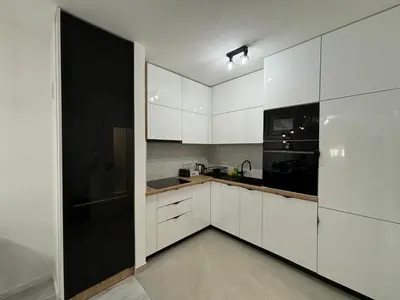 a kitchen with white cabinets and a black refrigerator at Amare Apartment in Livno