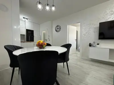 a dining room with a white table and black chairs at Amare Apartment in Livno