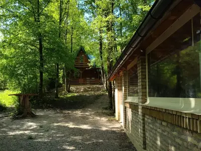 a log cabin in the woods next to a building at Bungalovi Krupa in Banja Luka