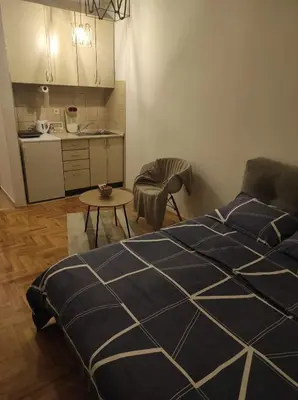 a bedroom with a bed and a table and a kitchen at Studio Maja in Banja Luka