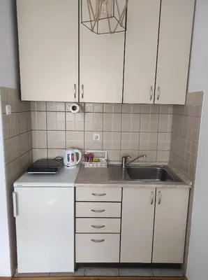 a small kitchen with white cabinets and a sink at Studio Maja in Banja Luka