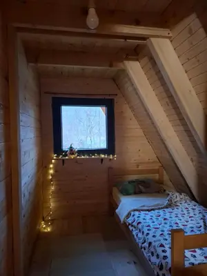 a small bedroom with a bed in a wooden house at Red Brick Guest House
