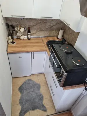 a small kitchen with a stove and white cabinets at Apartman Nina in Banja Luka