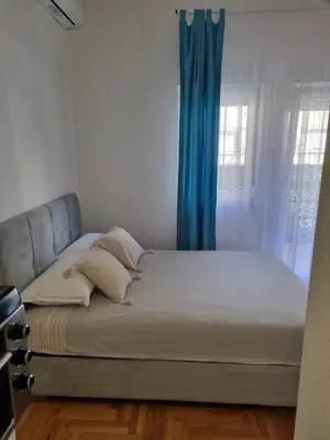 a bed in a room with a blue curtain at Apartman Nina in Banja Luka