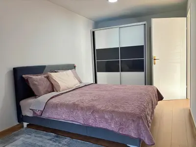 a bedroom with a bed with a purple comforter at Sanlej Apartman