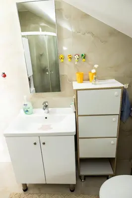 a white bathroom with a sink and a mirror at Sanlej Apartman