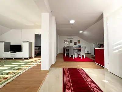 a living room with a table and a red rug at Sanlej Apartman